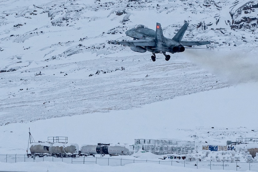 A jet soars in the air against a snowy backdrop.