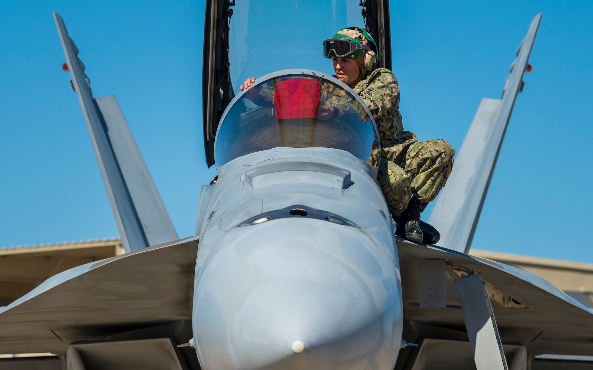 U.S. Navy AME3 Ariana Scott places a cover over the head-up guidance system inside an F/A-18E Super Hornet assigned to the “Flying Eagles” of Strike Fighter Squadron (VFA) 122, Lemoore, California, at Luke Air Force Base, Arizona, Feb. 7, 2023.