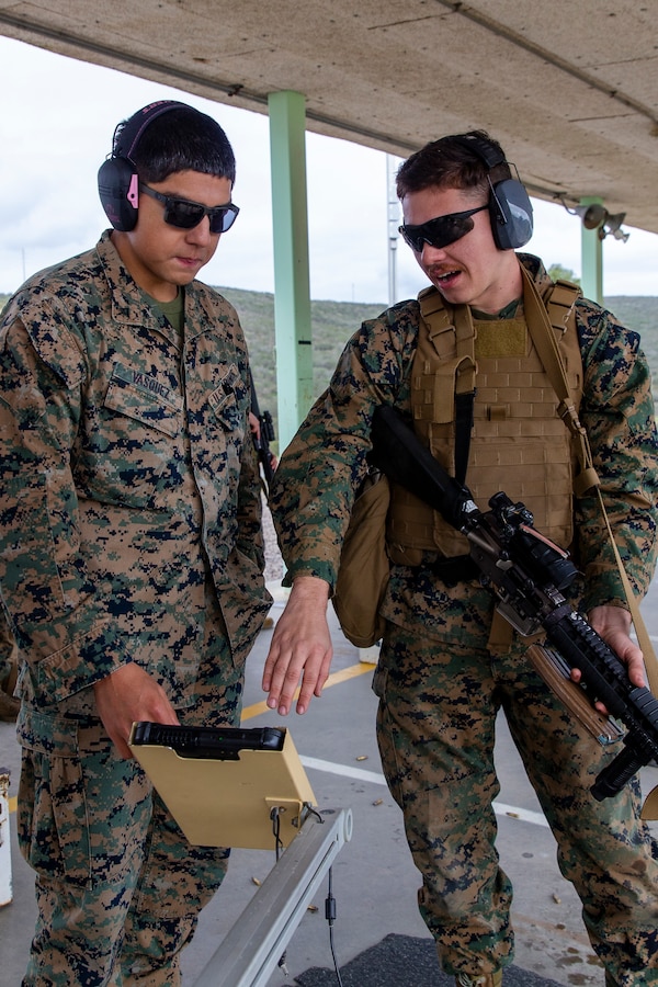 U.S. Marine Corps Lance Cpl. Aaron Vasquez instructs Lance Cpl. Anthony Vera on his shot grouping at Hathcock Range on Marine Corps Air Station Miramar, Jan. 30, 2023. Vasquez, a native of Los Angeles, California, is a marksmanship coach with Headquarters and Headquarters Squadron, MCAS Miramar, and Vera, a native of Tampa, Florida, is an aircraft maintenance support equipment electrician with Marine Aviation Logistics Squadron 16, Marine Aircraft Group 16, 3rd Marine Aircraft Wing. The LOMAH low-bar system can track shots on the target within a deviation of 17 millimeters. (U.S. Marine Corps Photo by Lance Cpl. Jackson Rush)