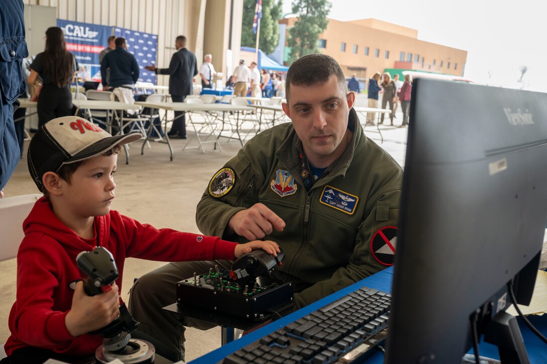 Capt. Benjamin "Vader" Kram, 31st Test and Evaluation Squadron teaches a young boy about how to use the flight simulator at California Aeronautical University Aviation Career Day in Bakersfield, California, Feb. 3.