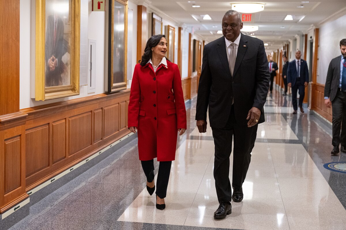 A man and woman walk down a hallway.