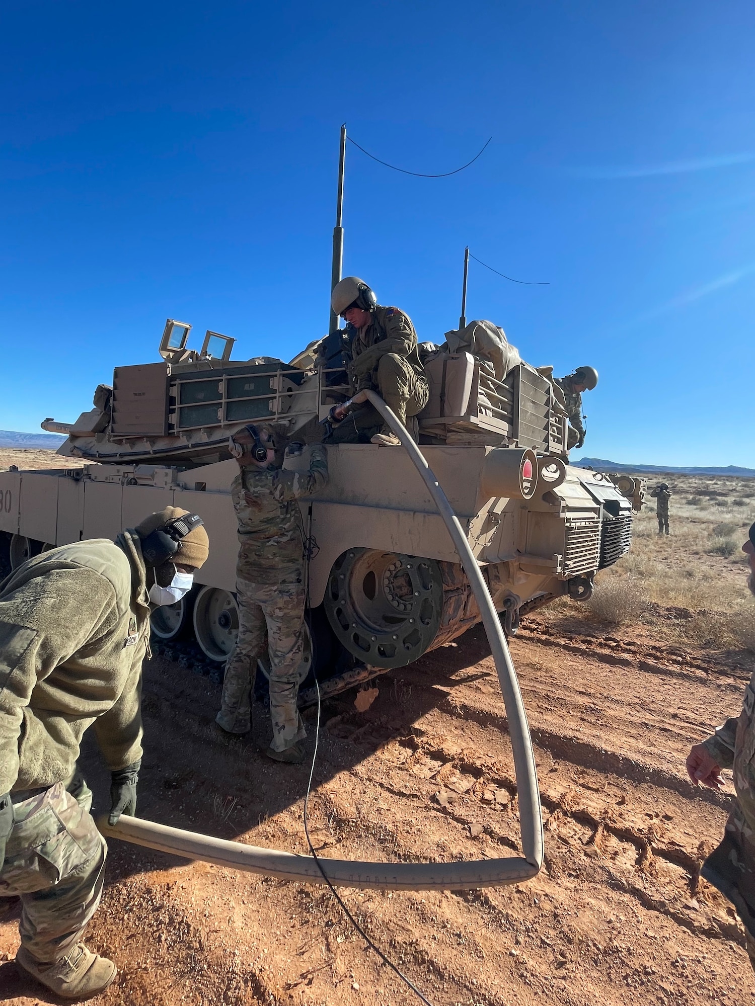 U.S. Army Soldiers assigned to the 1st Armored Division connect a fuel hose to an M1A2 Abrams Tank at Fort Bliss, Texas, Jan. 25, 2023. The 317th Airlift Wing executed an Agile Combat Employment exercise by sending a C-130 to the Fort Bliss Range to perform Specialized Fueling Operations with the 3rd Brigade Combat Team, 1st AD and the 1st Battalion, 77th Armored Regiment. The units successfully passed fuel from a C-130 to an M1A2 Abrams Tank utilizing an Emergency Response Refueling Equipment Kit, marking the first time in Air Force history that a C-130 has been used to refuel an Abrams tank. (Courtesy photo)