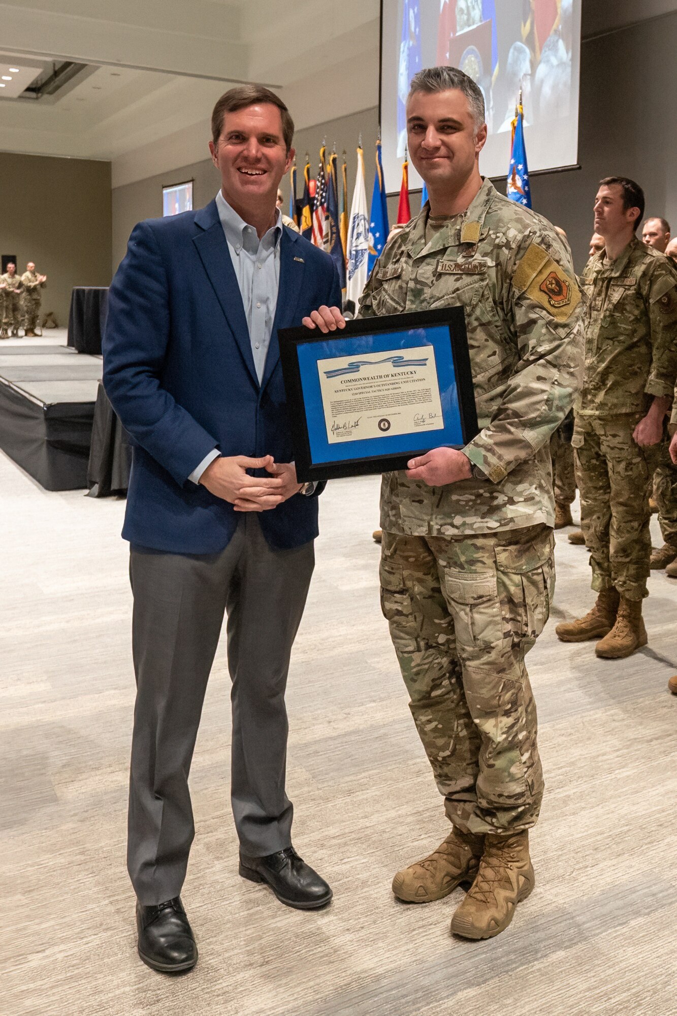 Gov. Andy Beshear, left, presents the Kentucky Governor’s Outstanding Unit Citation to Maj. Hunter Williams, commander of the Kentucky Air National Guard’s 123rd Special Tactics Squadron, during Leadership Development Day at the Kentucky Exposition Center in Louisville, Ky., Feb. 5, 2023. The award recognizes the unit’s rescue efforts following tornadoes and flooding that struck the Commonwealth in 2021 and 2022. The Airmen cleared 140,000 square feet of rubble at a collapsed factory, evacuated 40 flood victims and recovered four missing children. (U.S. Air National Guard photo by Dale Greer)