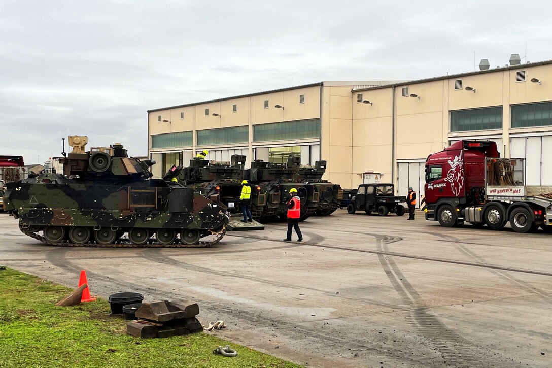 Workers inspect tanks outside a building.