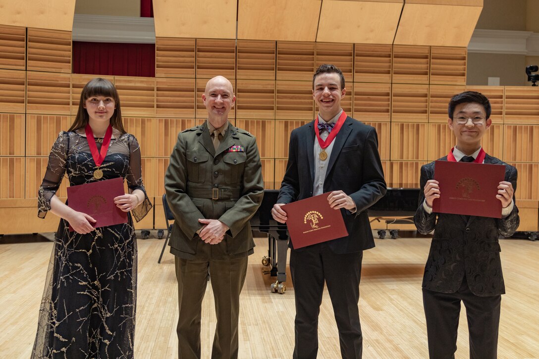 Marine Band Director Col. Jason K. Fettig stands with the winners of the 2023 concerto competition. Left to Right: Flutist Nikka Gershman (third place), Bassoonist Nathan Shepherd (second place), Oboist Kyle Cho (first place).