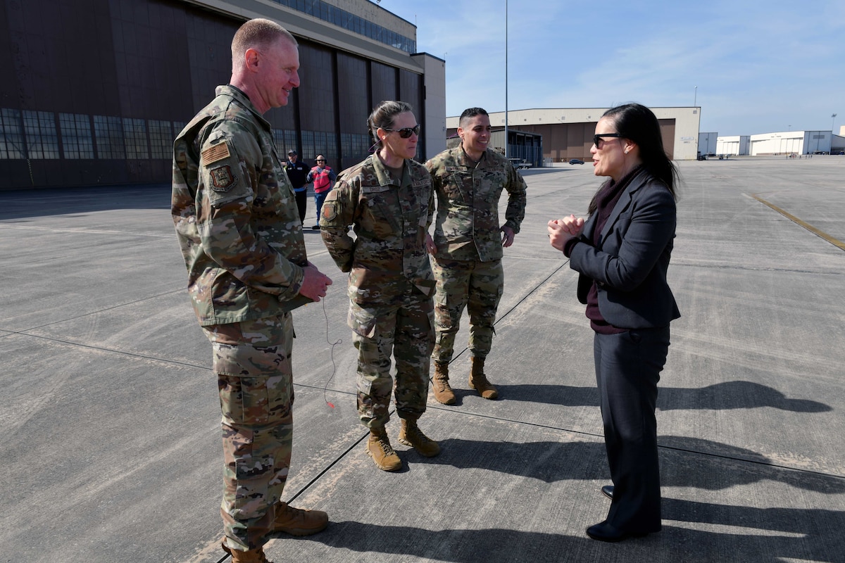 Photo shows people standing on flight line talking to each other