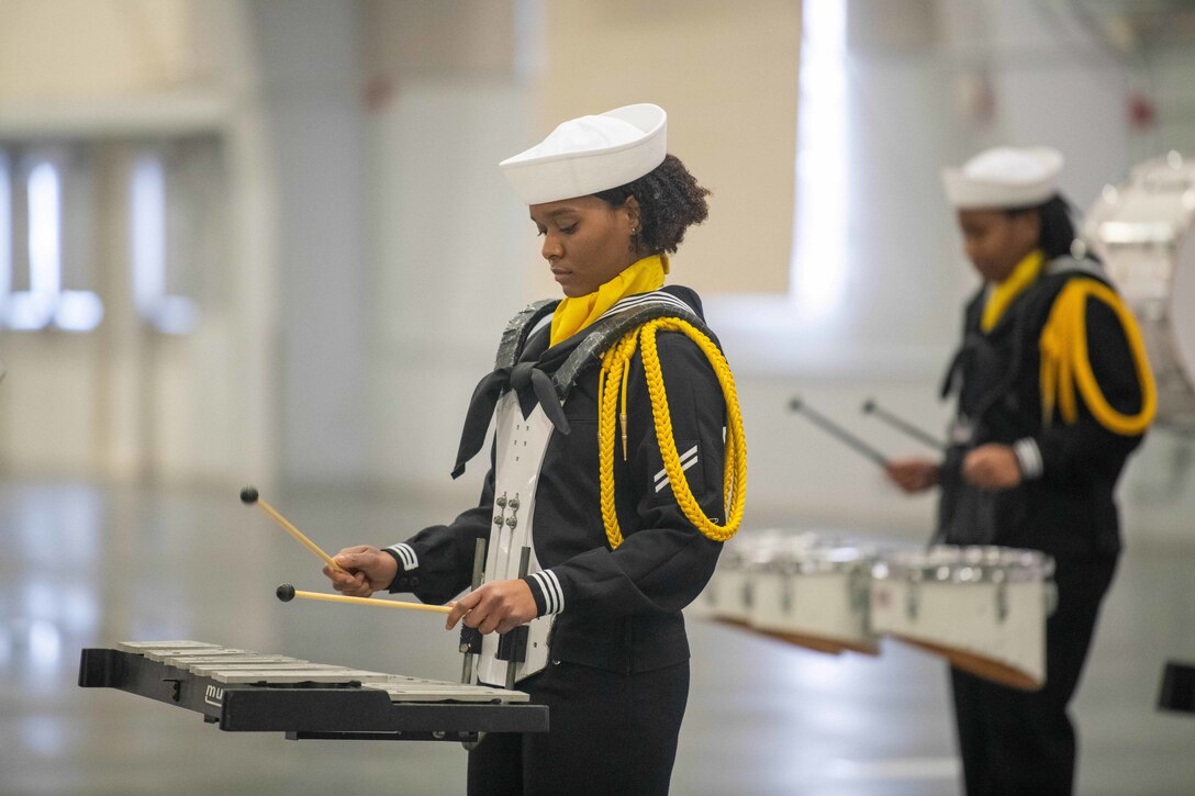 Two Navy recruits play instruments during a ceremony.