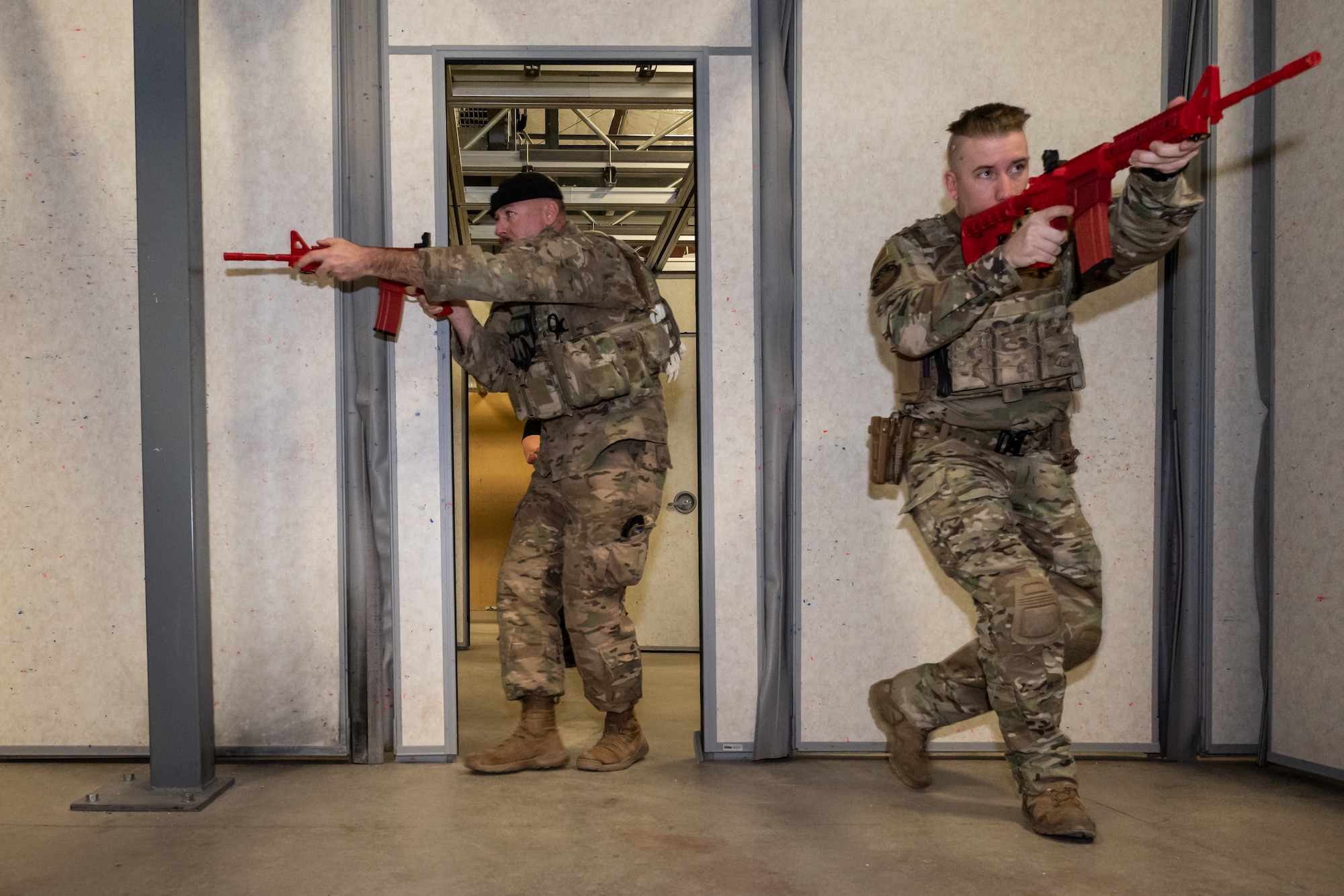 Two individuals with rifles enter a room through a doorway