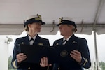 Capt. Breanna Knutson (left), commander Coast Guard Sector North Bend, Oregon, reads an award with Chief Warrant Officer Beth Slade (right) during Coast Guard Station Coos Bay's change of command ceremony in Coos Bay, Oregon, Jun. 10, 2022. Slade was congratulated for her efforts in helping a pregnant member who assisted in the betterment of women's retention in the Coast Guard. (U.S. Coast Guard photo by Petty Officer 3rd Class Diolanda Caballero)