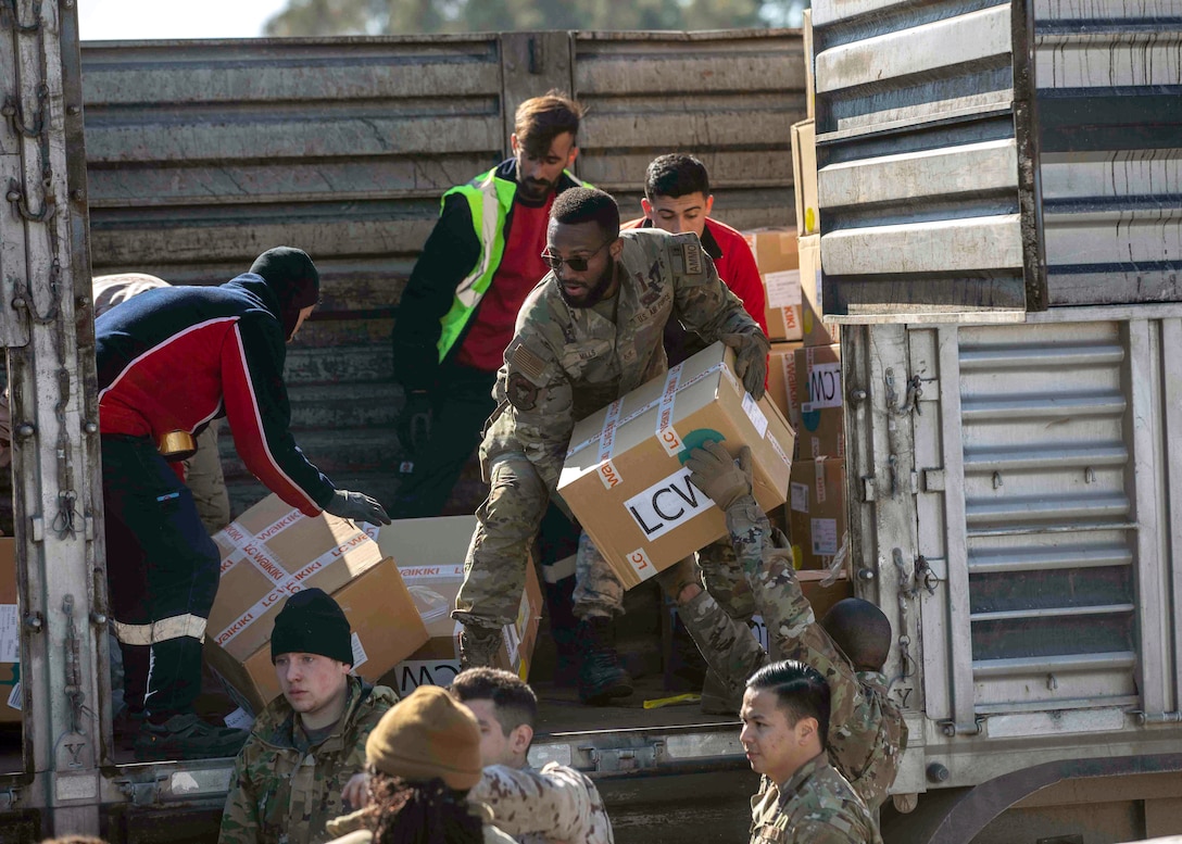 Airmen pass boxes to load a supply truck.