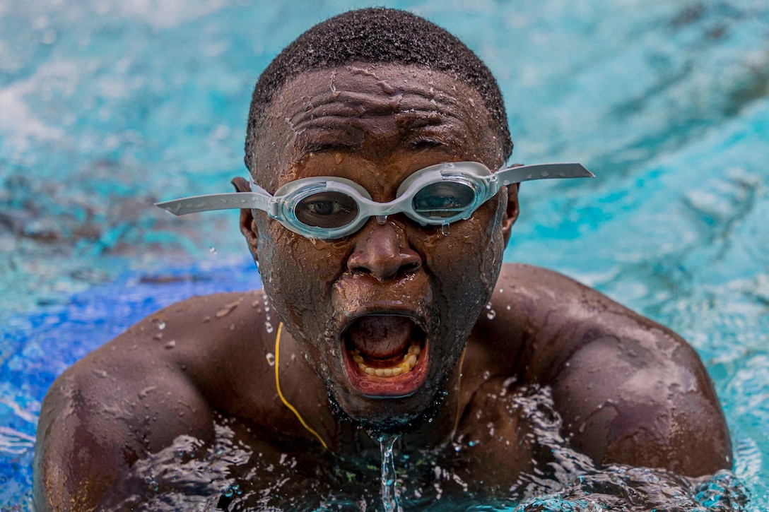 A service member swims in a pool.