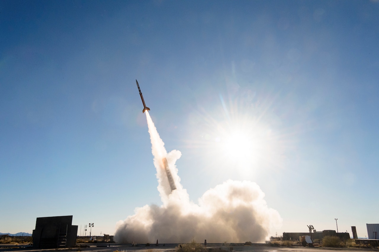 Smoke fills the air as a missile launches under a sunlit sky.