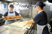 Petty Officer 3rd Class Valerie Slunaker and Petty Officer 2nd Class Alysha Joseph (right) make fried chicken aboard the Coast Guard Cutter Dallas Feb. 14, 2012.