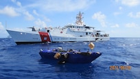 An unseaworthy migrant craft sits in front of the Coast Guard Cutter Isaac Mayo, 27 miles south of Long Key, Florida, June 9, 2021. A law enforcement team from the cutter interdicted 16 Cuban migrants from the craft. (U.S. Coast Guard photo)