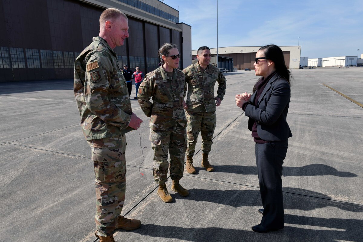 Photo shows people standing on flight line talking to each other