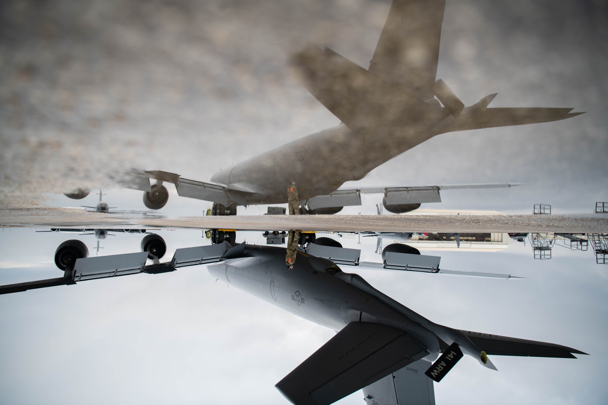 An Airman and an aircraft are reflected in a pool of water.