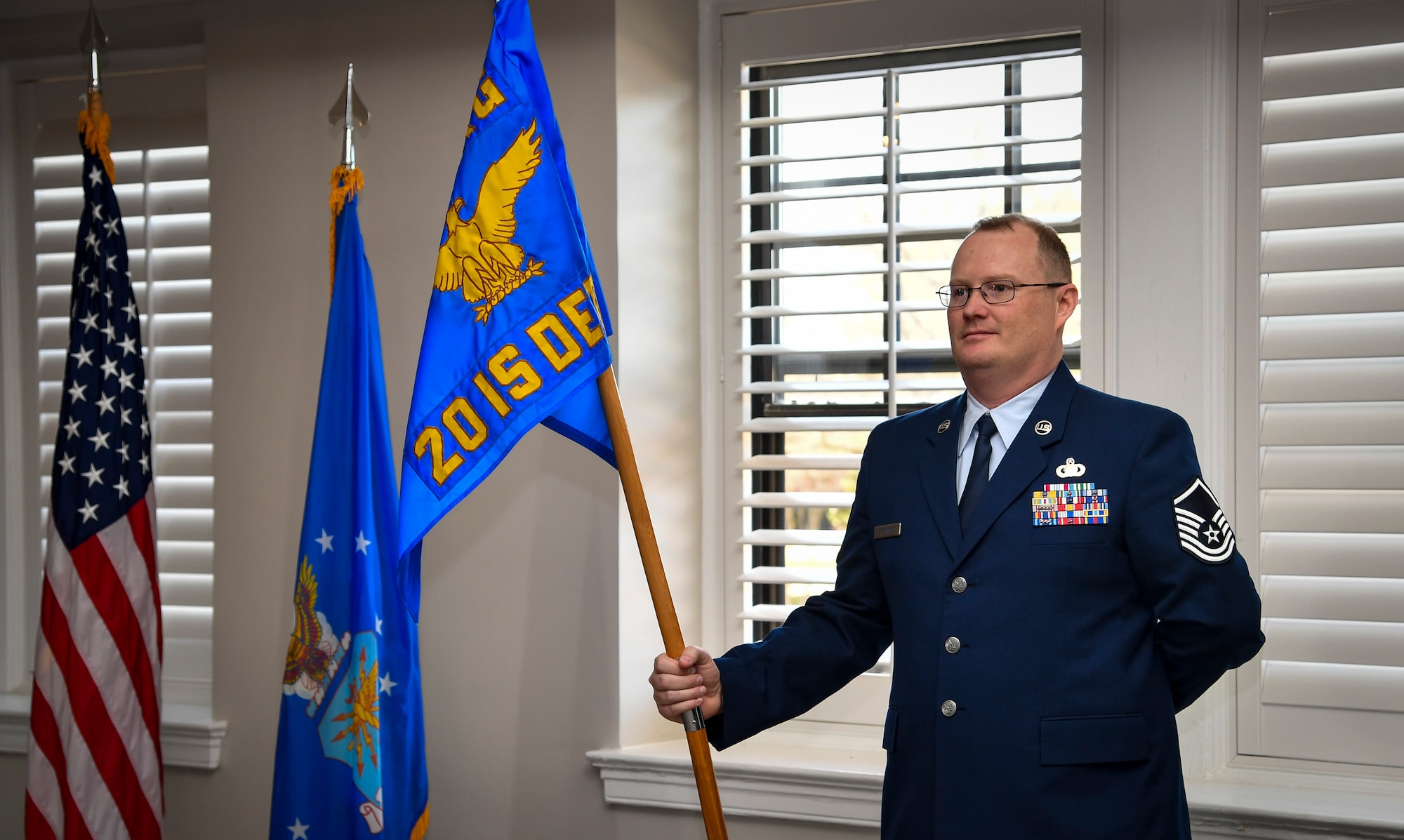 An Airman stands at parade rest holding guidon.