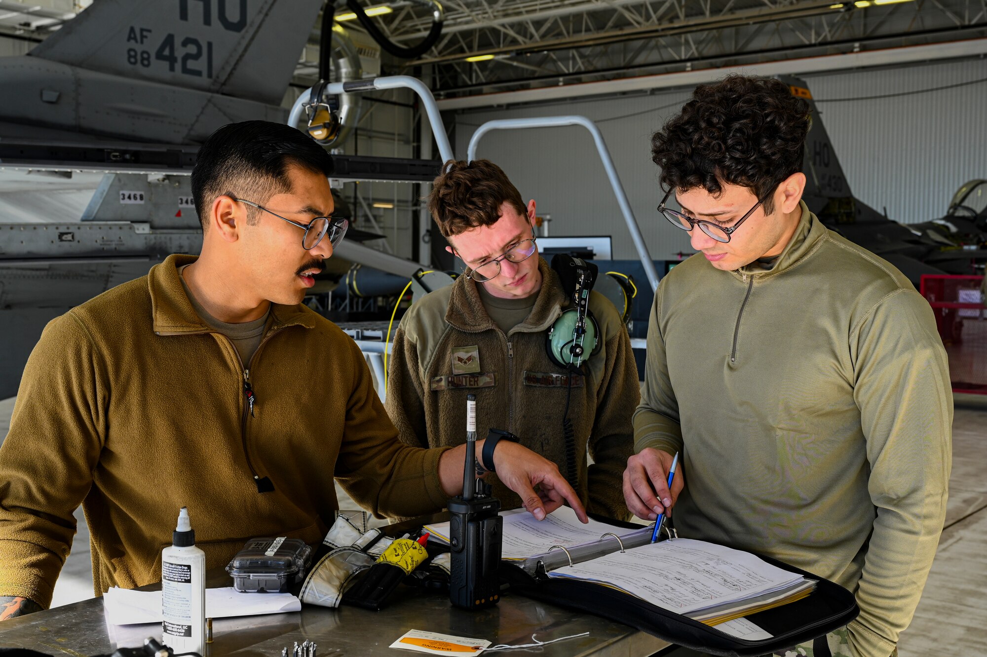 U.S. Air Force Staff Sgt. Brandon Millare, 49th Component Maintenance Squadron fuels craftsman, left, U.S. Air Force Senior Airman William Hunter, 49th CMS fuels journeyman, center, and U.S. Air Force Staff Sgt. Luis Ayala, 49th CMS fuels craftsman, look through maintenance documents at Holloman Air Force Base, New Mexico, Feb. 8, 2023. The 49th CMS provides maintenance to all F-16 Vipers on base and ensures that each aircraft is operational for combat effectiveness.  (U.S. Air Force photo by Airman 1st Class Isaiah Pedrazzini