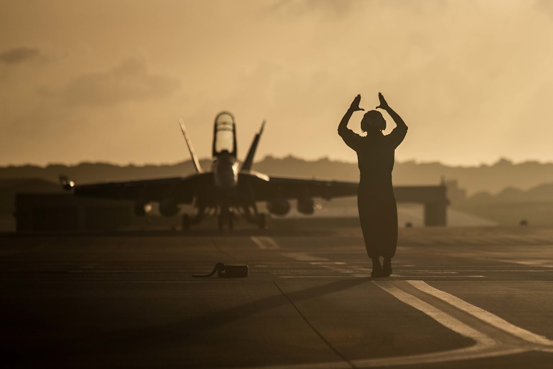 U.S. Marine Corps Cpl. John Gonzales, a powerline mechanic with Marine Fighter Attack Squadron 312, guides an aircraft to a hangar after flight operations during Exercise Cope North 2023 at Andersen Air Force Base, Guam, Feb. 9, 2023. Cope North is an annual, multilateral field training exercise that allows each partner nation to hone vital readiness skills while enhancing interoperability during the execution of various mission sets, to include air superiority, interdiction, electronic warfare, tactical airlift, and aerial refueling.