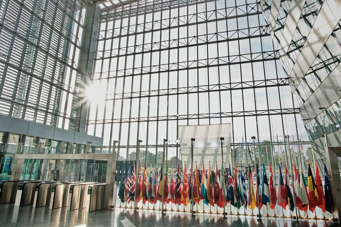 An airy lobby-type room with glass walls and a display of flags.