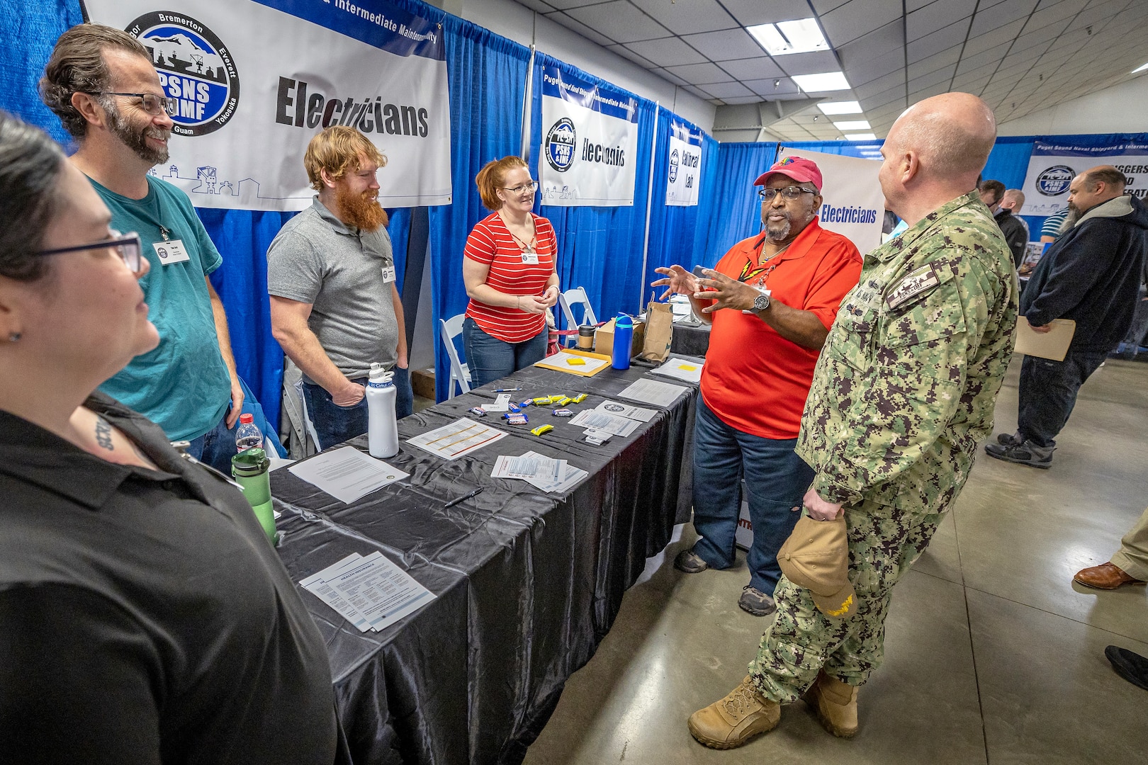 Capt. Jip Mosman, commander, Puget Sound Naval Shipyard & Intermediate Maintenance Facility, visits with representatives from Code 950, the PSNS & IMF Electronics Shop, during a hiring fair Feb. 3, 2023, at the Kitsap County Fairgrounds, in Bremerton, Washington. (U.S. Navy photo by Scott Hansen)