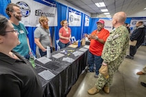 Capt. Jip Mosman, commander, Puget Sound Naval Shipyard & Intermediate Maintenance Facility, visits with representatives from Code 950, the PSNS & IMF Electronics Shop, during a hiring fair Feb. 3, 2023, at the Kitsap County Fairgrounds, in Bremerton, Washington. (U.S. Navy photo by Scott Hansen)