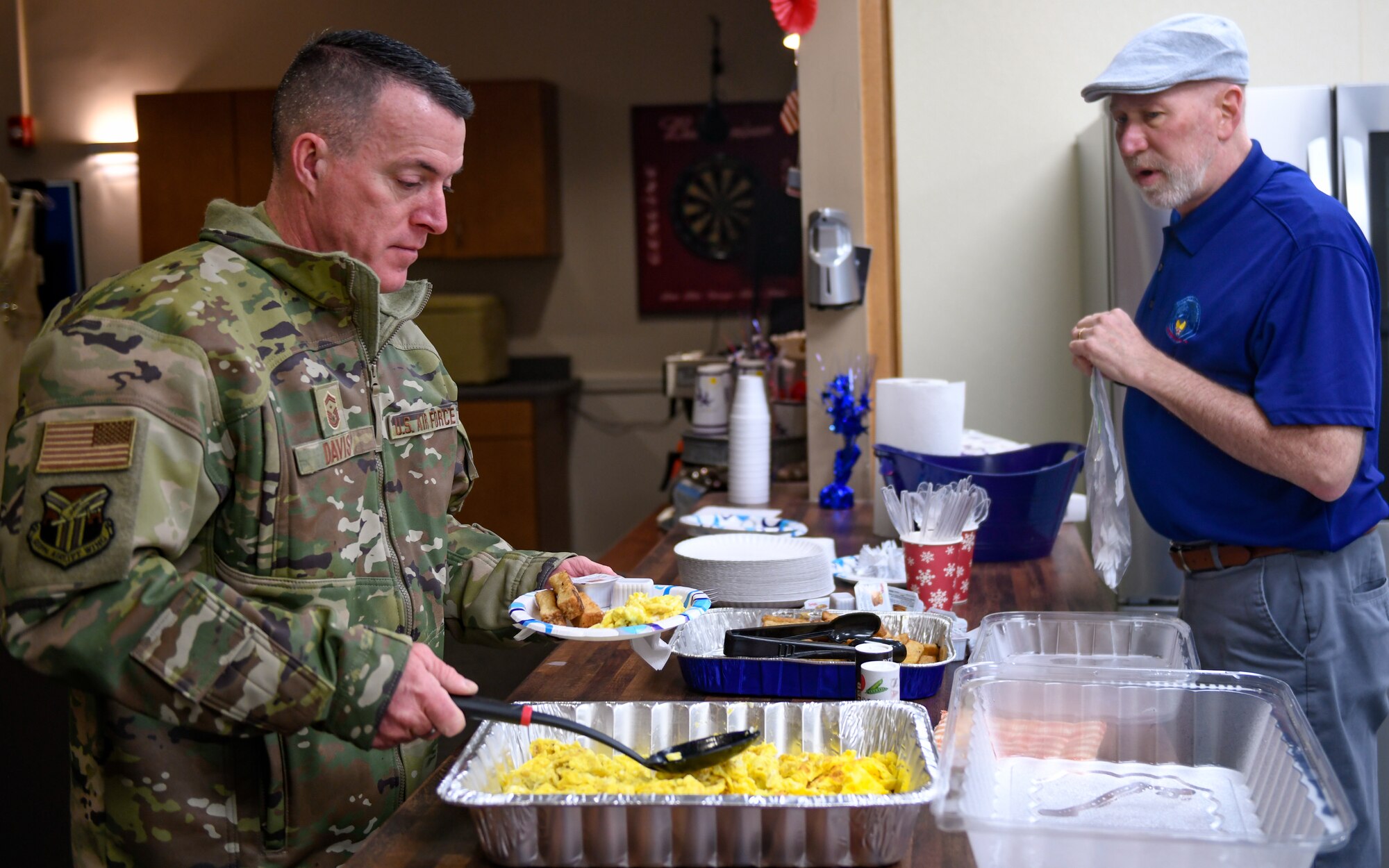 Senior Master Sgt. John Davis, first sergeant assigned to the 910th Aircraft Maintenance Squadron, plates his breakfast as Jim Naughton, director of the Military and Family Readiness Center, sets out silverware, Feb. 3, 2023, at Youngstown Air Reserve Station, Ohio.