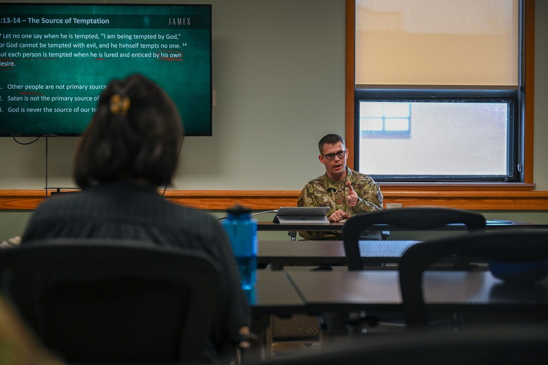 Air Force chaplain sitting at a desk and talking to group.