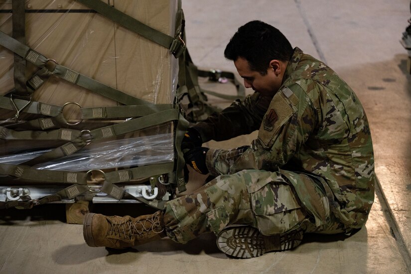 Airman tightens straps on pallet.