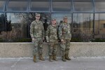 Three military members in uniform pose for a group photo