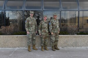 Three military members in uniform pose for a group photo