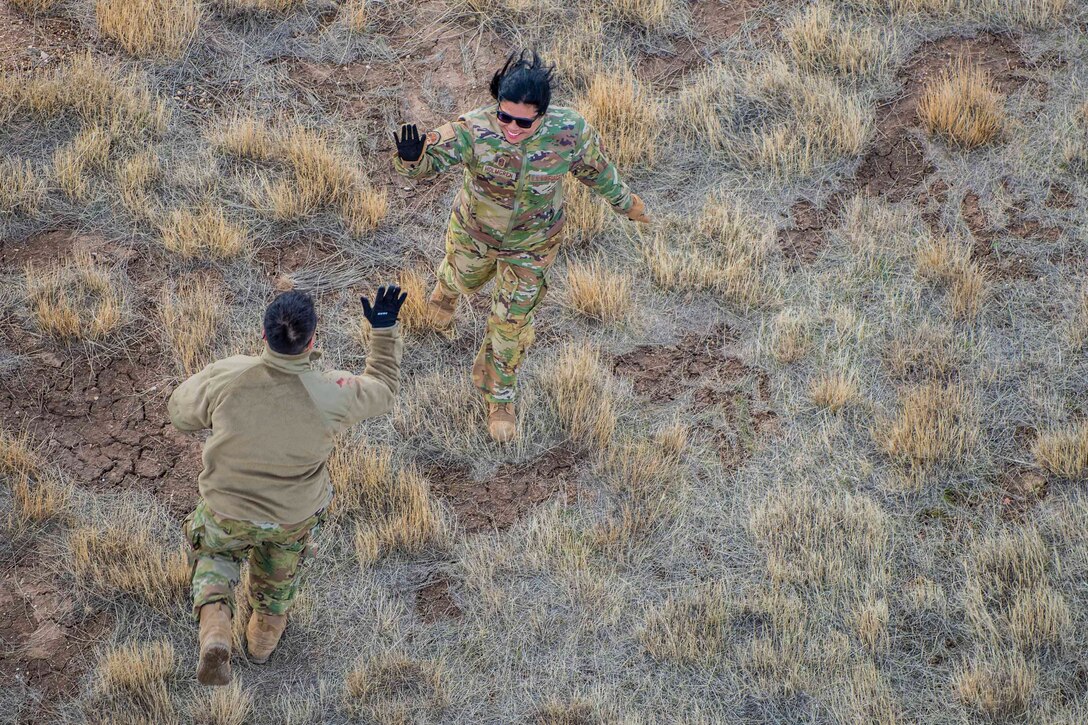 Two guardsmen prepare to high five each other in a field.
