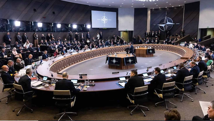 People sit at a very large oval table in a big room.