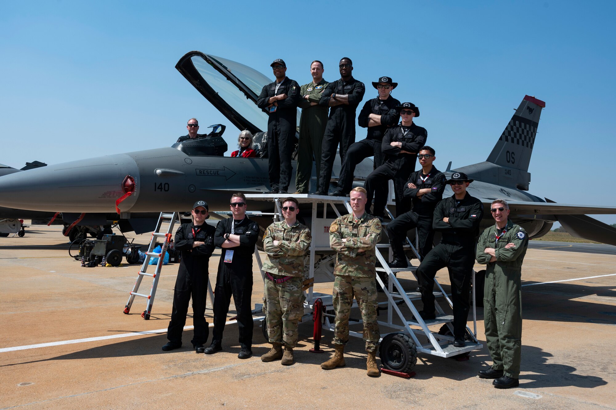 Group photo with members of the Pacific Air Forces F-16 Demonstration Team with plane behind them.