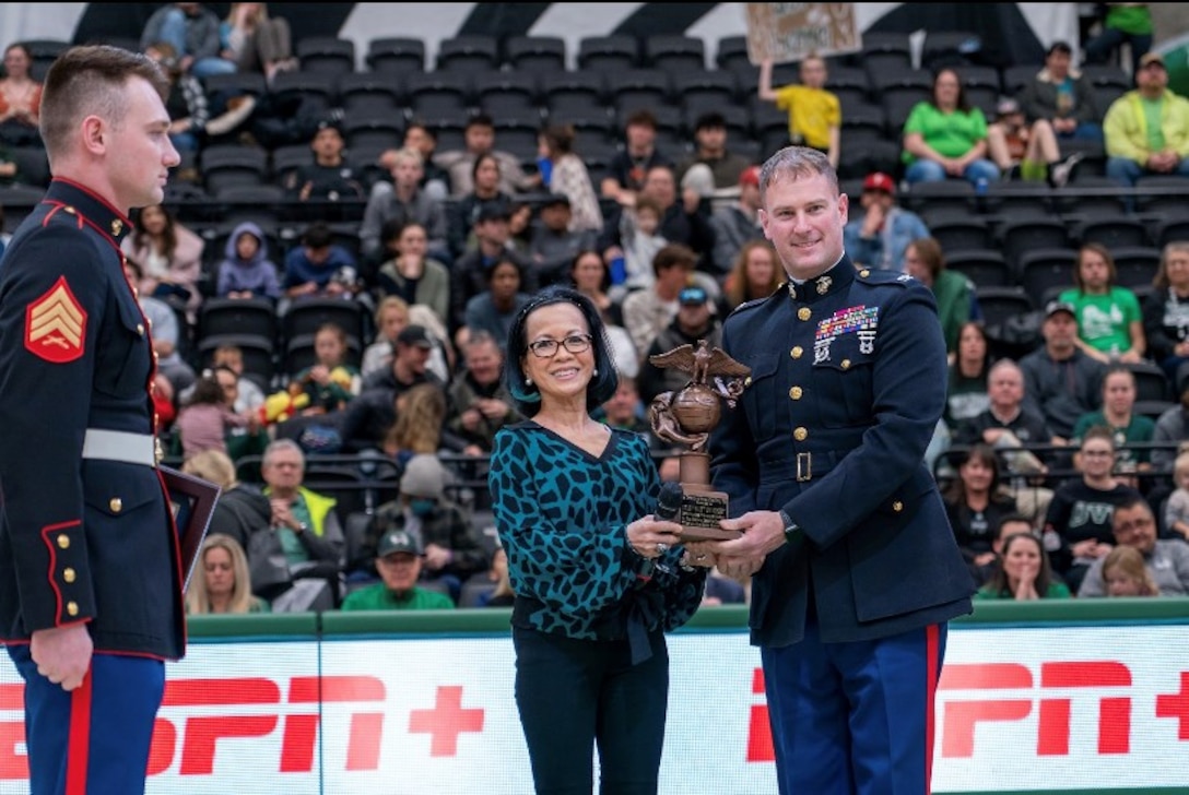 U.S. Marine Corps Col. Warren Cook Jr., the Commanding Officer of 8th Marine Corps District, and Marines with Officer Selection Station Salt Lake City had the privilege of recognizing Sergeant Nolan M. Hicken as the recipient of The Commandant’s Trophy during a salute to service basketball game at Utah Valley University (UVU) on February 8, 2023.  The Commandants trophy is awarded to high performing Candidates for notable leadership and superior accomplishments while at Marine Corps Officer Candidates School. 
The UVU President, Dr. Astrid Taminez also received a trophy in recognition of the University’s outstanding preparation of students.  Over the last 4 years there have been 12 students and alumni of UVU that have been selected to attend Marine Corps Officer Candidates School to become Marine Officers that will help win our nations futures battles.