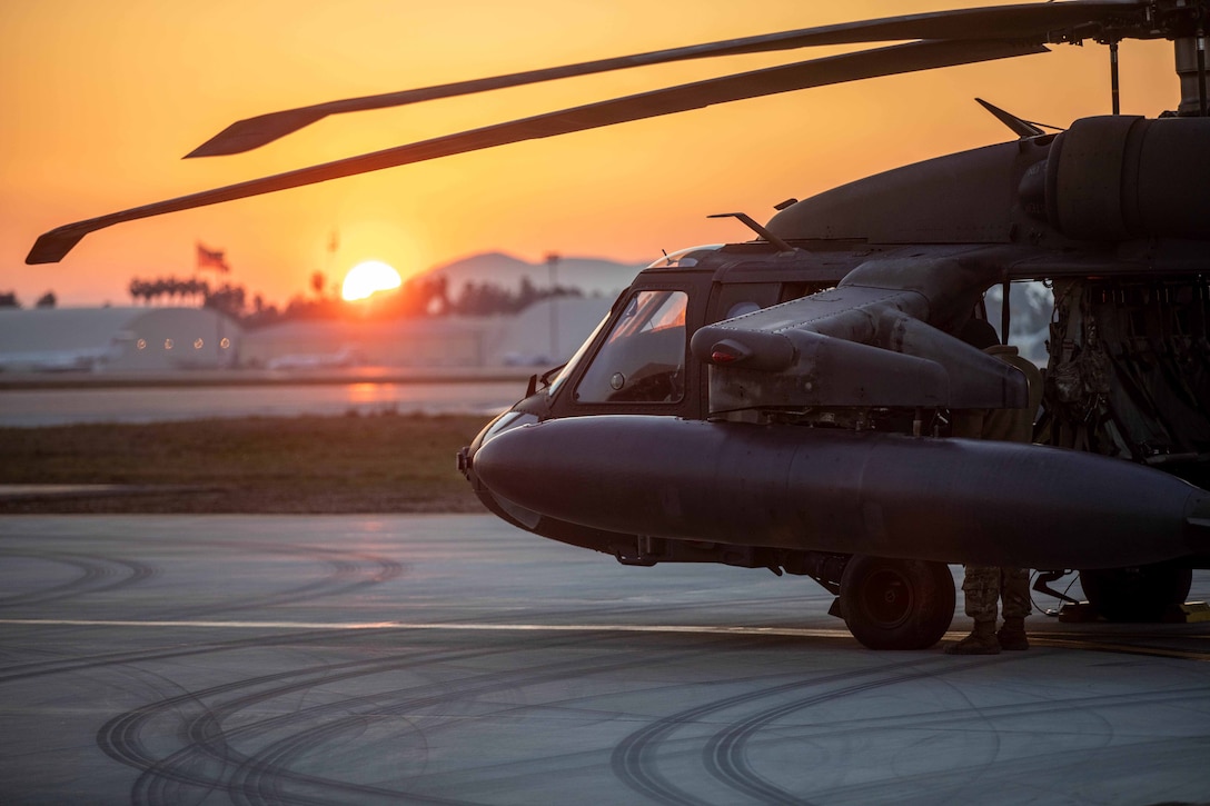 A helicopter sits on the tarmac at twilight.