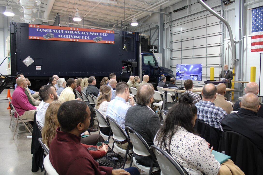 Members of the CBRN Defense community sit down during a presentation to celebrate the Analytical Laboratory System - Modification Work Order's achievement of full operational capacity