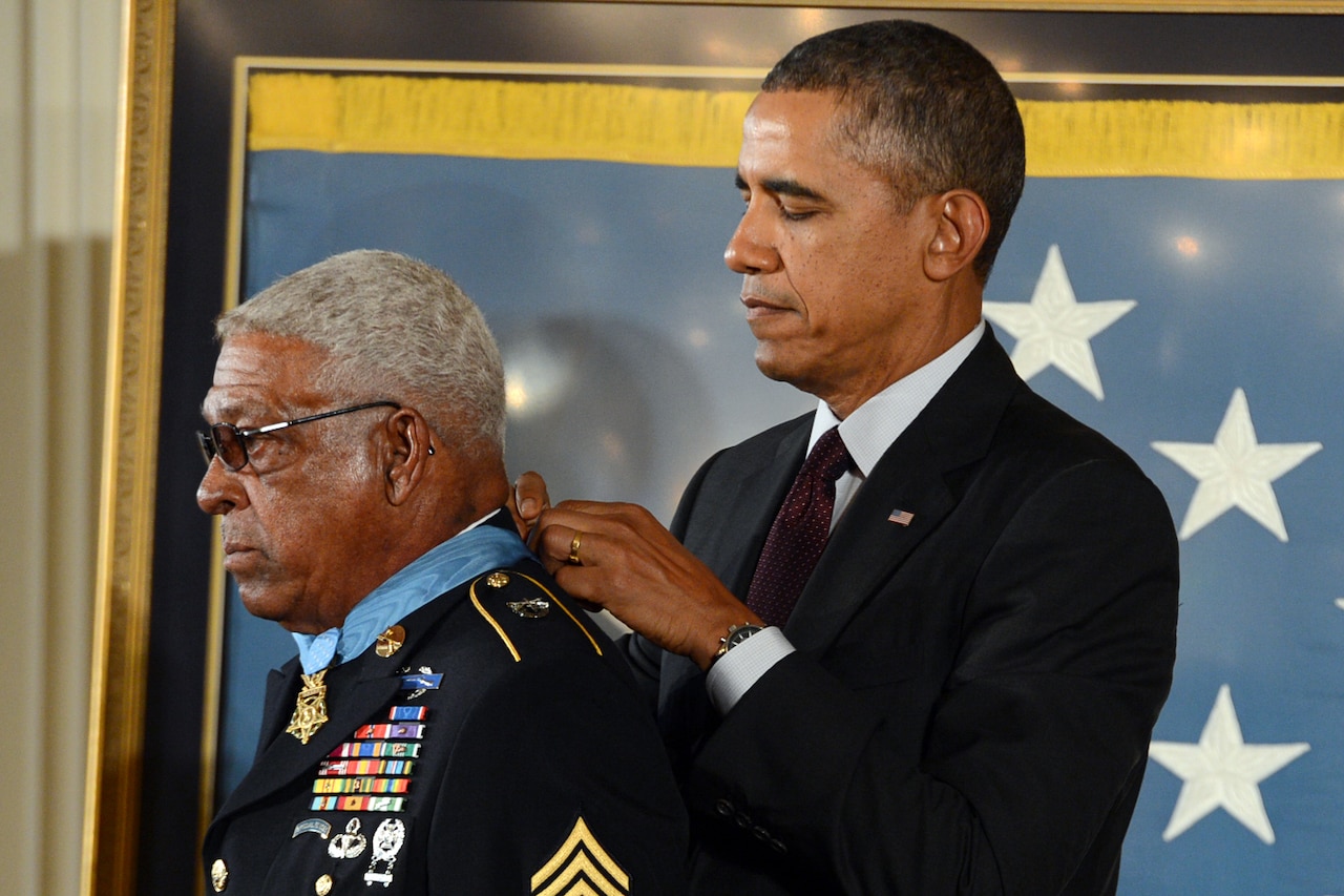 President Obama puts a medal on a man's neck