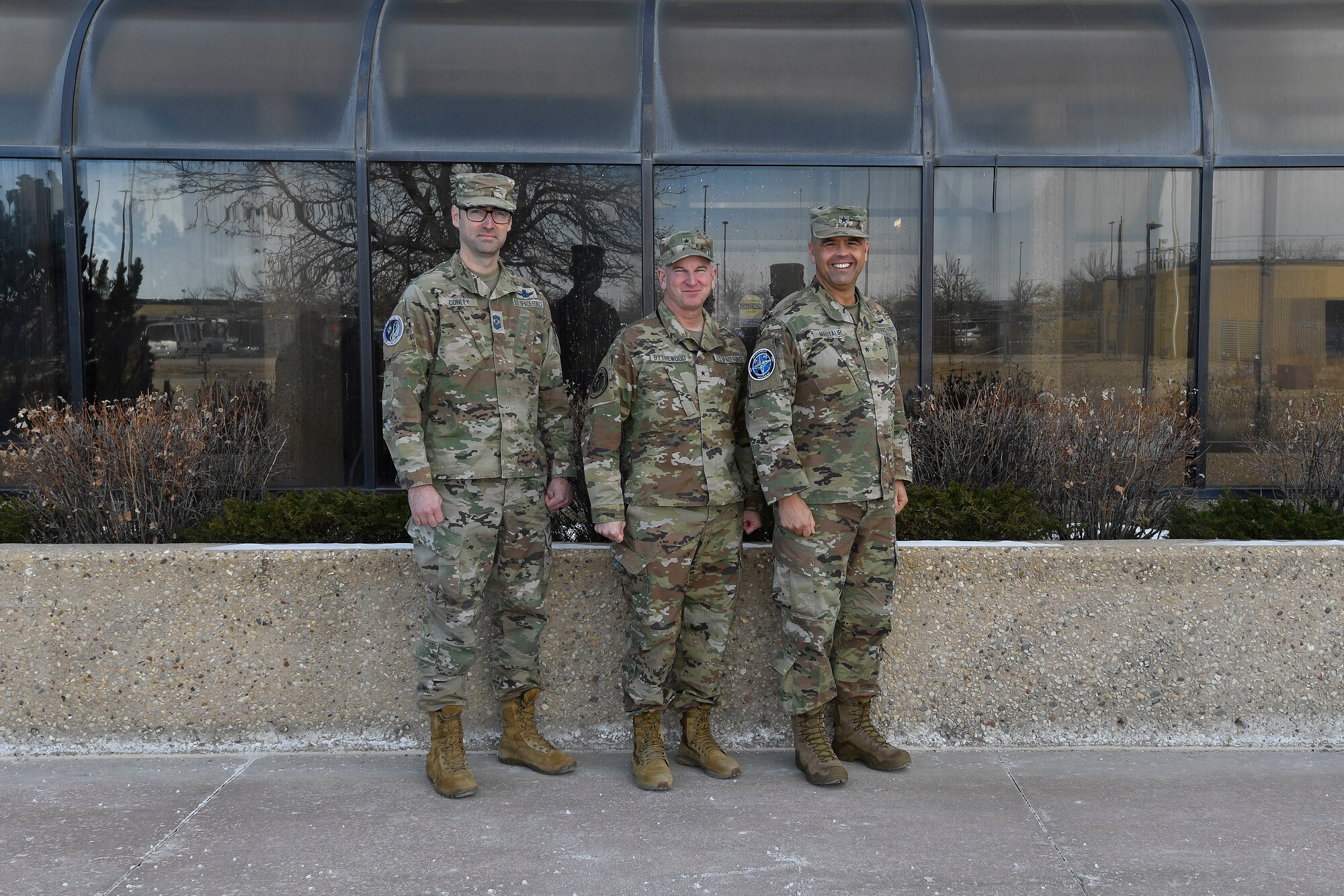 Three military members in uniform pose for a group photo