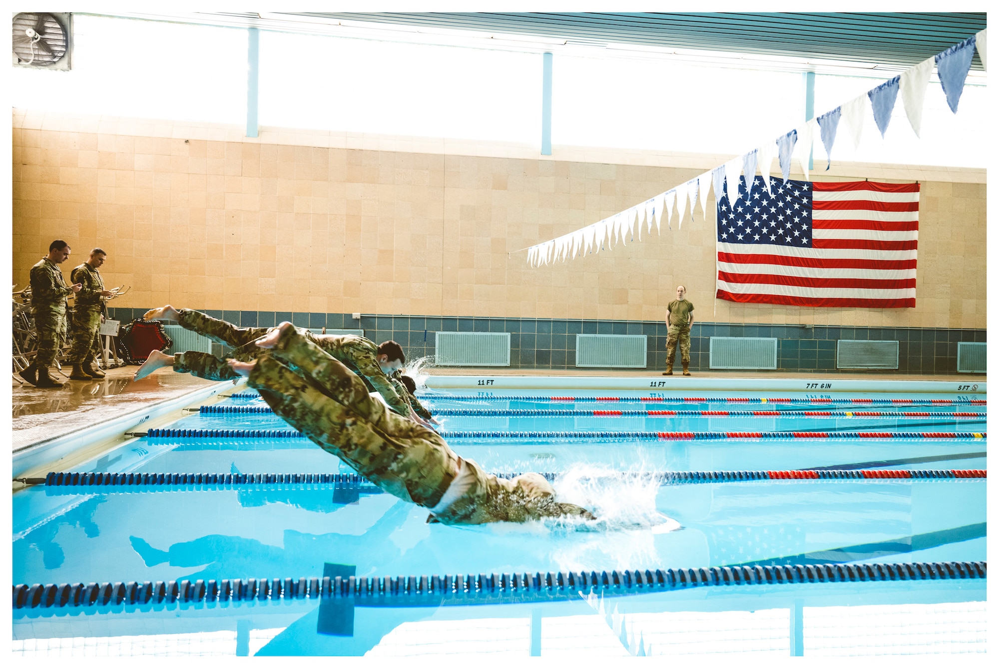 Airmen dressed in their operational camouflage pattern uniforms dive into the pool as part of German Armed Forces Proficiency Badge testing Feb. 1 at Dodge Fitness Center on Wright-Patterson Air Force Base, Ohio.