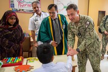 230215-N-EG592-1073 KARACHI, Pakistan (Feb. 15, 2023) Vice Adm. Brad Cooper, commander of U.S. Naval Forces Central Command (NAVCENT), U.S. 5th Fleet and Combined Maritime Forces, shakes hands with a child at the Special Children School at Pakistan Naval Station Karsaz in Karachi, Feb. 15, 2023. NAVCENT personnel delivered physical therapy and mobility equipment to the school.