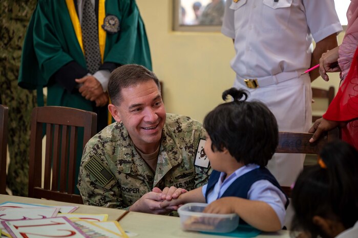 230215-N-EG592-1281 KARACHI, Pakistan (Feb. 15, 2023) Vice Adm. Brad Cooper, commander of U.S. Naval Forces Central Command (NAVCENT), U.S. 5th Fleet and Combined Maritime Forces, shakes hands with a child at the Special Children School at Pakistan Naval Station Karsaz in Karachi, Feb. 15, 2023. NAVCENT personnel delivered physical therapy and mobility equipment to the school.