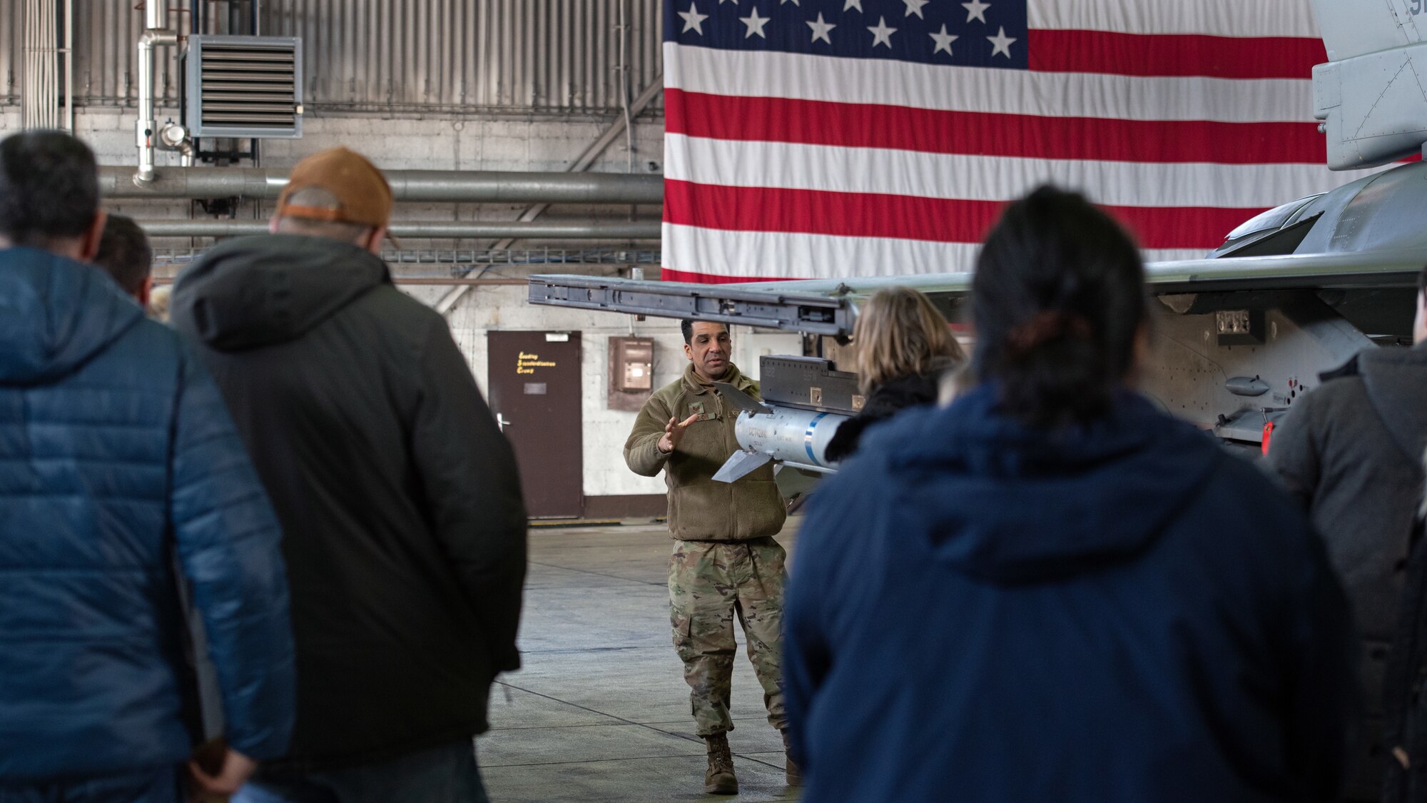 Civilian employees look at a jet.