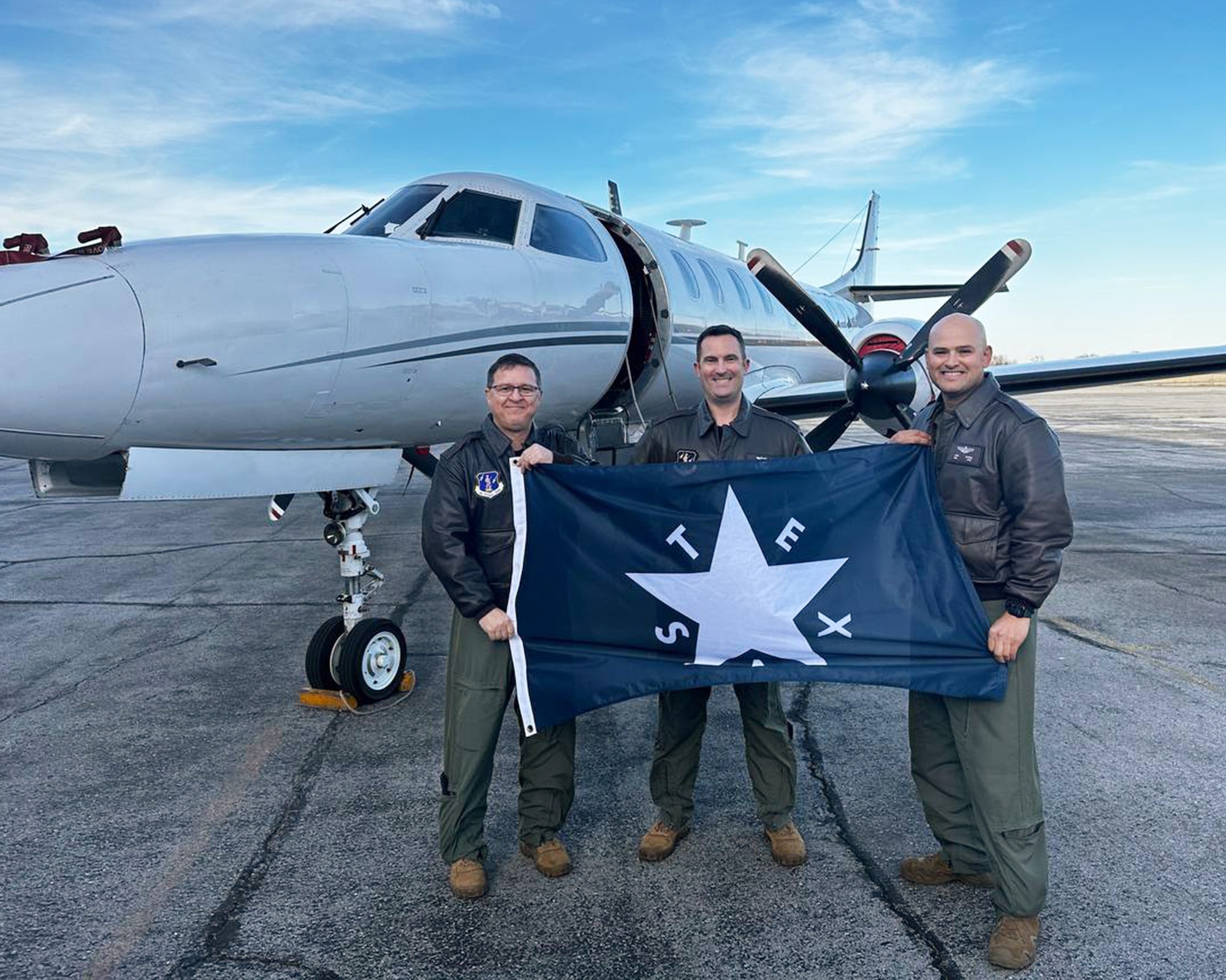 RC-26 crew members pose in front of their aircraft.