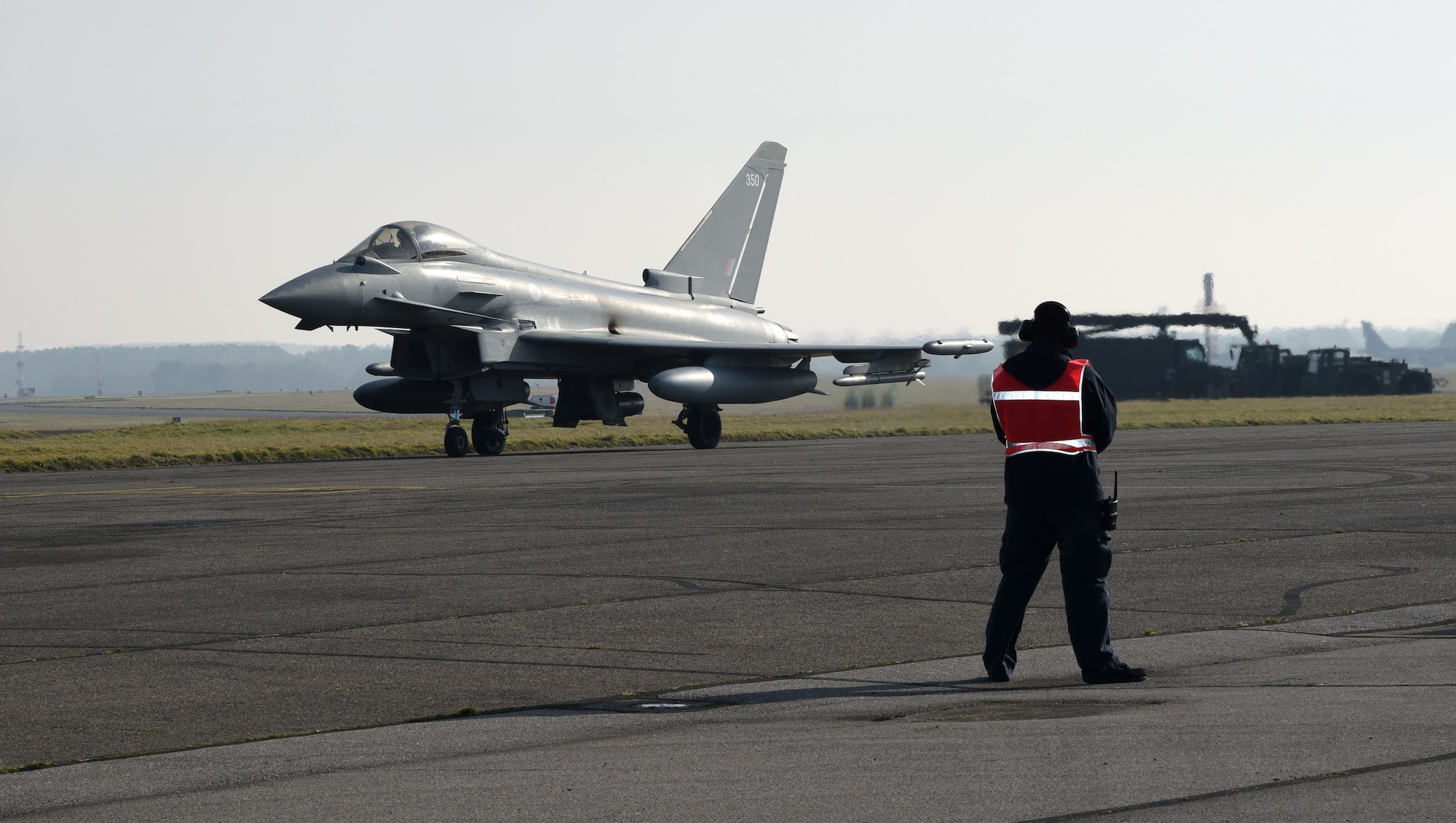A Eurofighter Typhoon FGR4 taxis from a hardstand as it prepares to take off after being marshalled out by a Team Mildenhall member from transient alert at Royal Air Force Mildenhall, England, Feb. 15, 2023. The aircraft, from RAF Coningsby, England, diverted here due to bad weather. The Typhoon is a highly capable and extremely agile multi-role combat aircraft, and the pilot performs many essential functions through the aircraft’s hands on throttle and stick interface which, combined with an advanced cockpit and the helmet equipment assembly, renders the Typhoon superbly equipped for all aspects of air operations. (U.S. Air Force photo by Karen Abeyasekere)