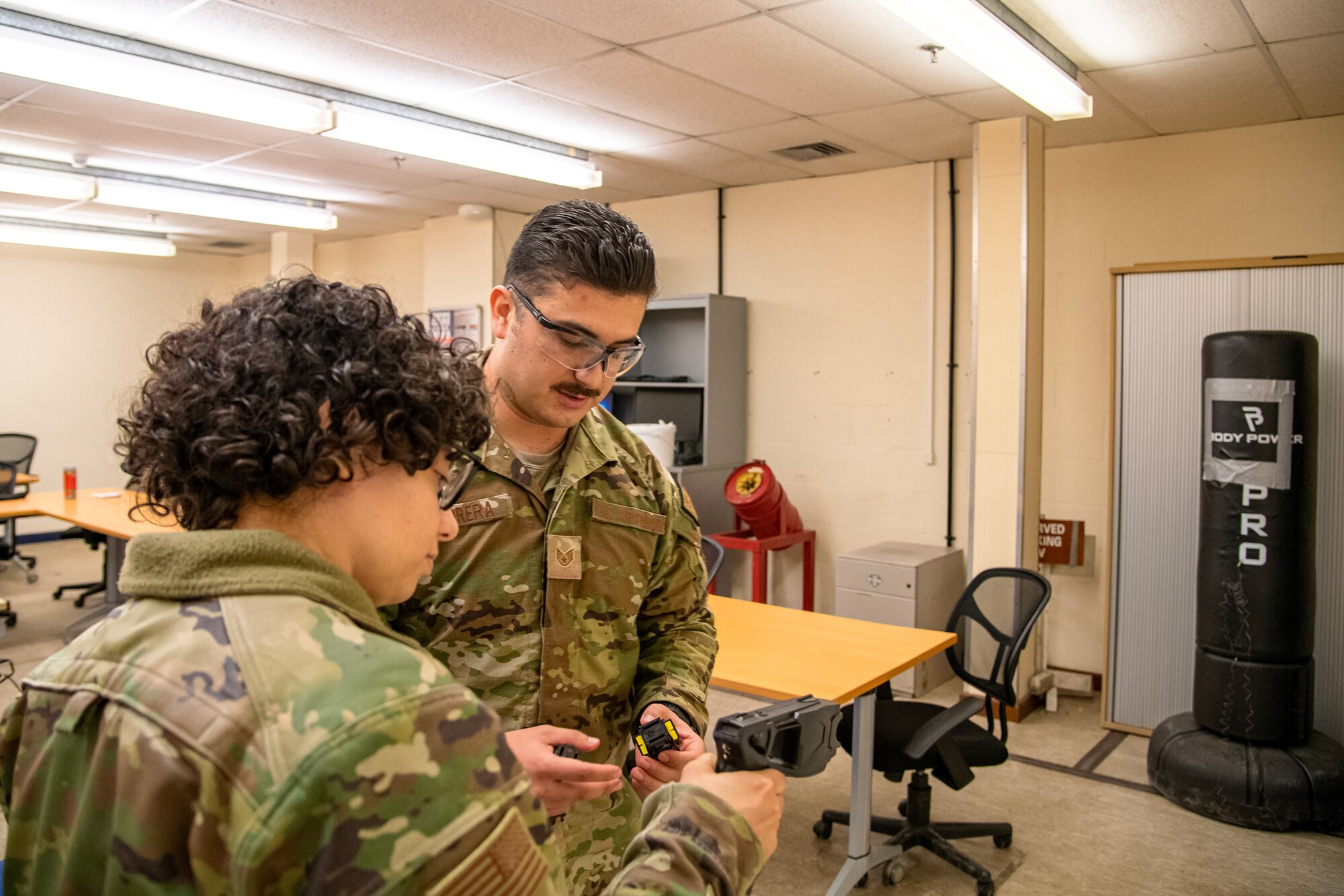 U.S. Air Force Staff Sgt. Andres Carbrera, 423d Security Forces Squadron flight sergeant, right, provides instruction on proper Taser handling techniques during a non-lethal combatives qualification course at RAF Alconbury, England, Feb. 7, 2023. The course provided Defenders with the skills and knowledge to properly detain a suspect using non-lethal combative methods. (U.S. Air Force photo by Staff Sgt. Eugene Oliver)