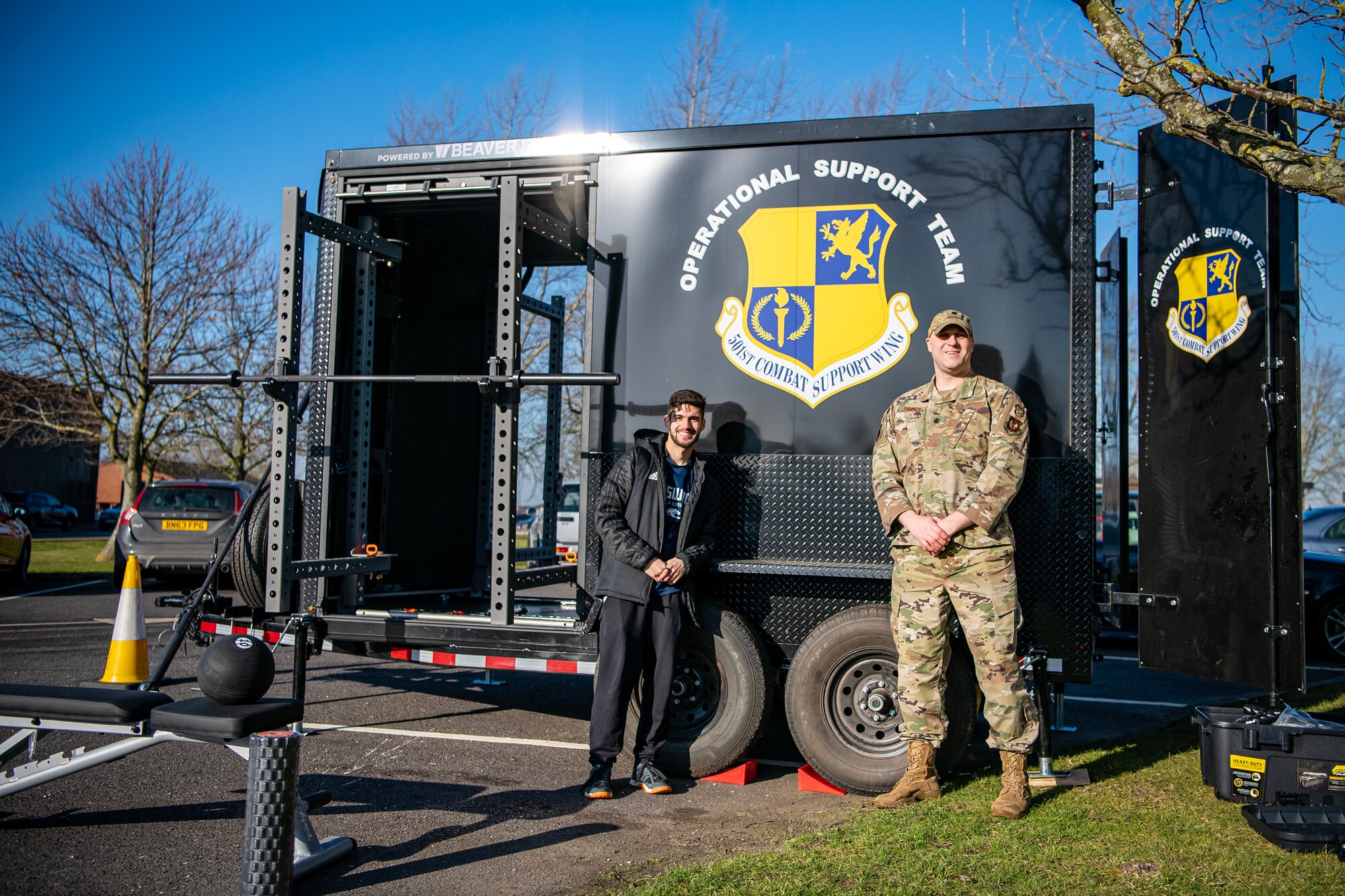 Members of the 501st Combat Support Wing Human Performance Optimization team stand in front of a BeaverFit Mobile Gym at RAF Alconbury, England, Feb. 7, 2023. The HPO team uses various methods to integrate with units across the wing  providing Airmen additional resources for improving  mental and physical readiness. (U.S. Air Force photo by Staff Sgt. Eugene Oliver)