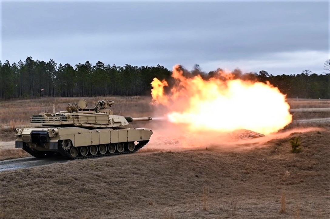 A tank fires in a field.