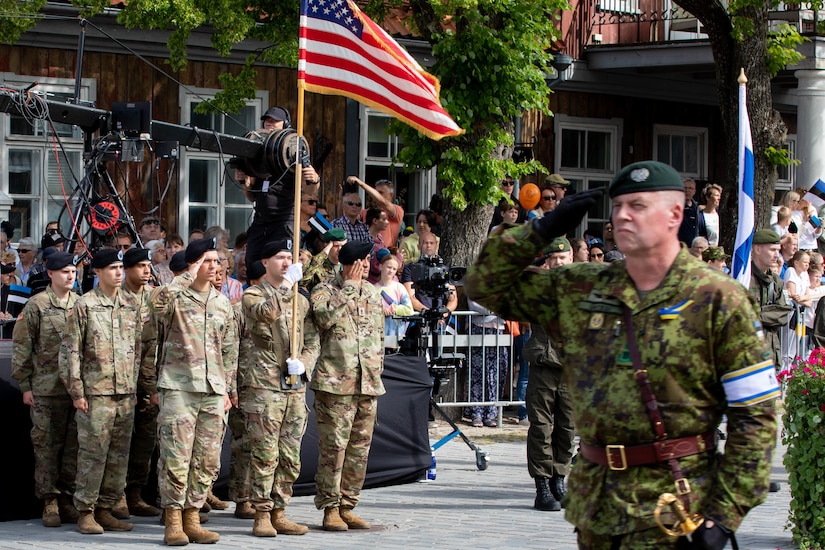 Soldiers salute as an officer passes the U.S. flag.