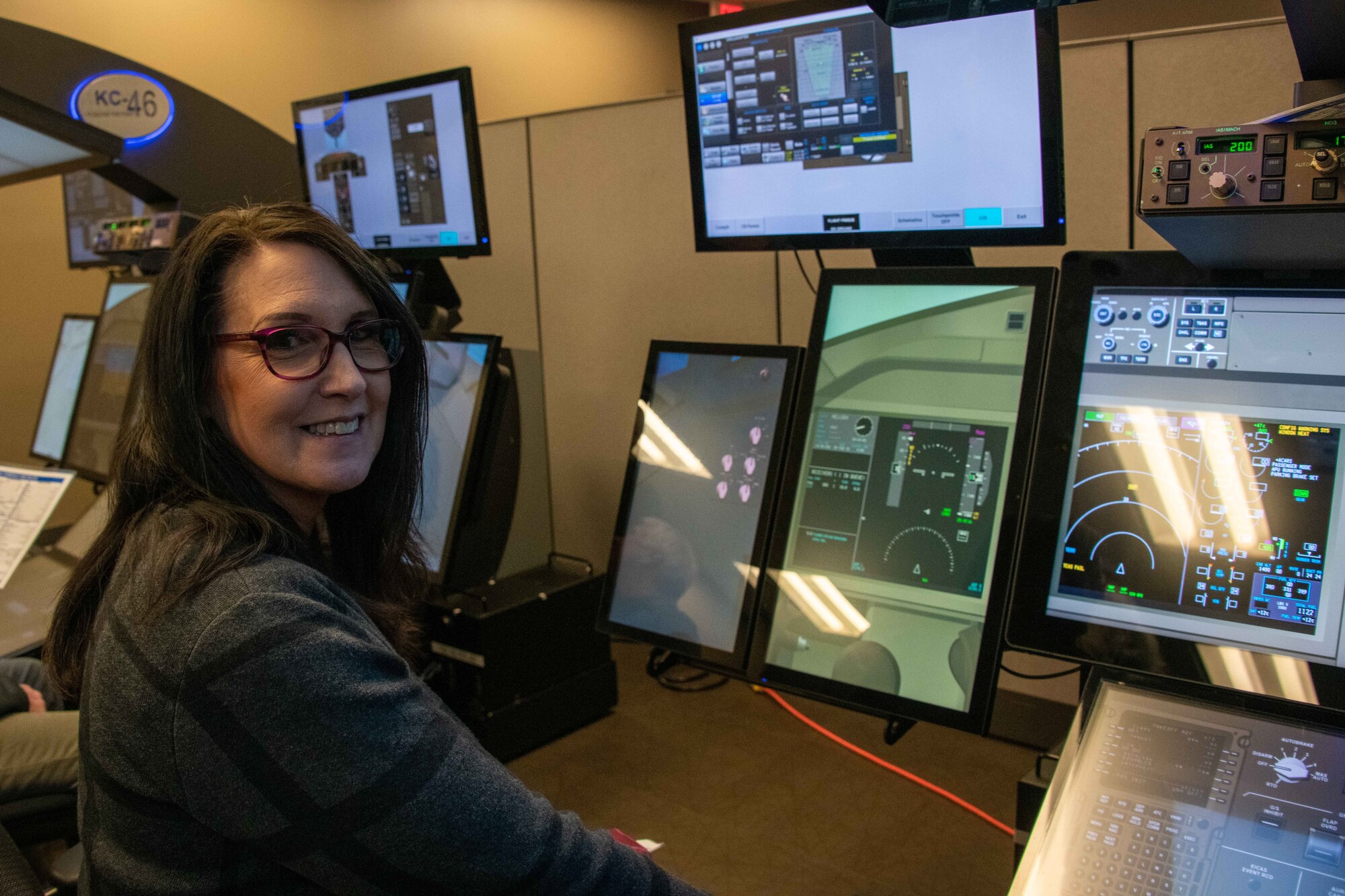 Mary Quantrell, former 62nd Aerial Port Squadron honorary commander, smiles as she orients herself with a KC-46 Pegasus simulator at Altus Air Force Base, Oklahoma, Feb. 9, 2023. Tony Valerio, KC-46 Aircrew Training System site manager, gave the civic leaders a brief on the new simulators, which teaches students the plane’s controls as well as how to operate in emergency situations without any additional risks. (U.S. Air Force photo by Airman 1st Class Kari Degraffenreed)
